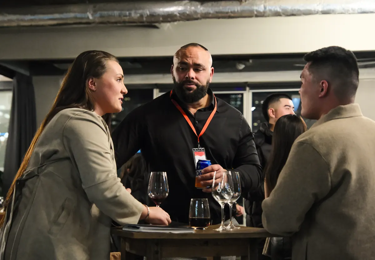 Three members talking at a high table with wine glasses at a BNB Success event.