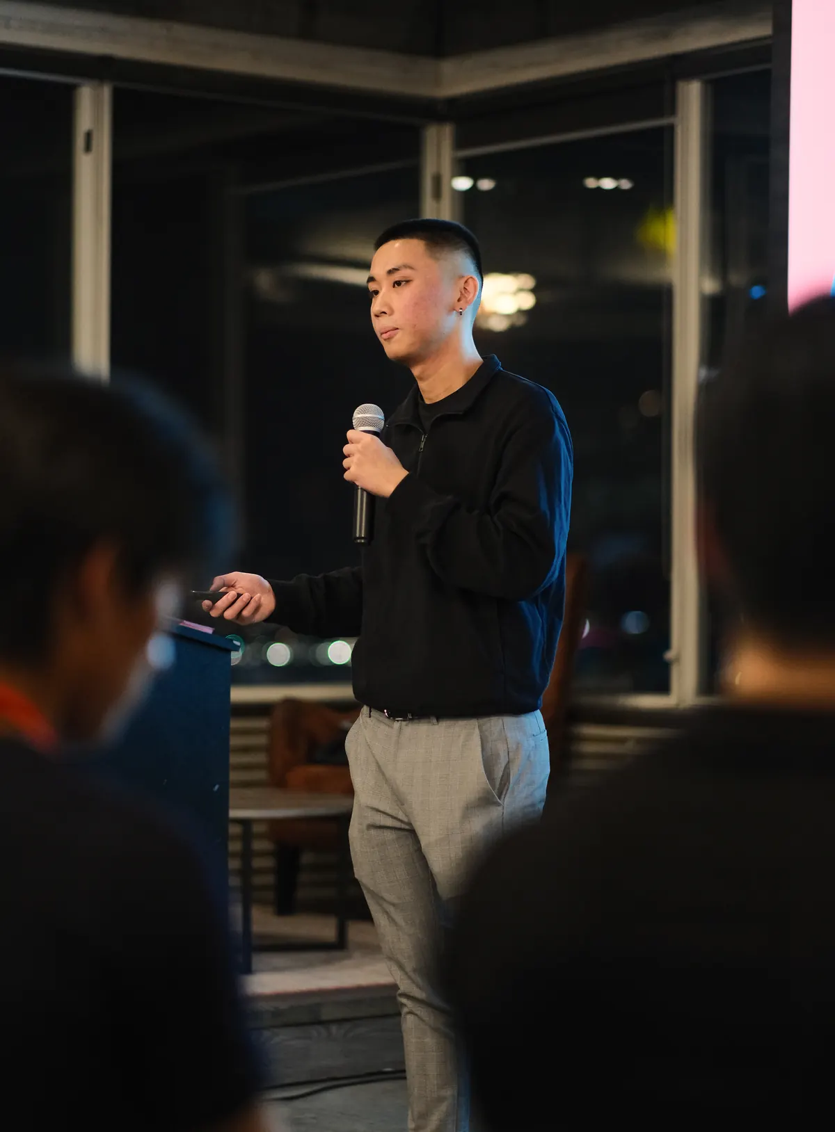 Jordan Pham speaking with a microphone at a BNB Success event at night.